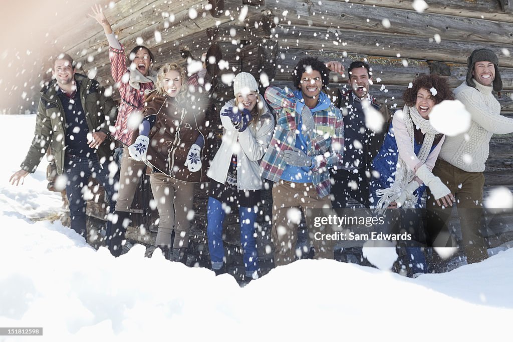 Porträt von lächelnden Freunde werfen Schneebälle vor der Kabine