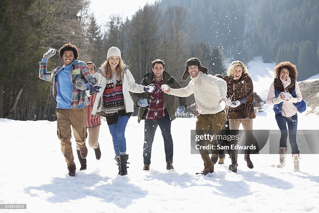 Souriant amis lancer des boules de neige dans le champ