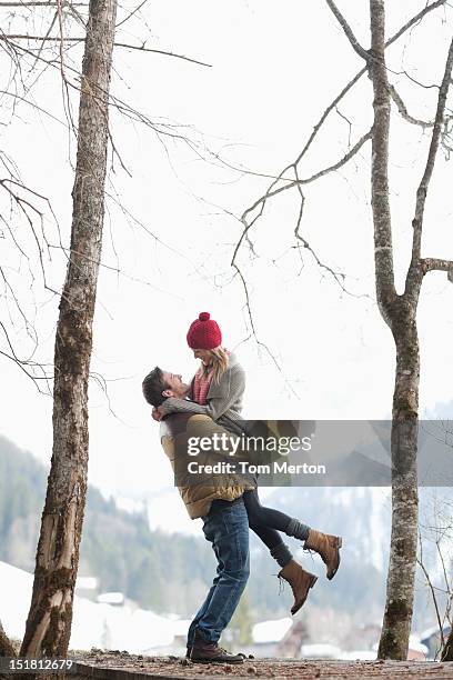 mann gewichtheben frau im schnee wald - winter couple stock-fotos und bilder