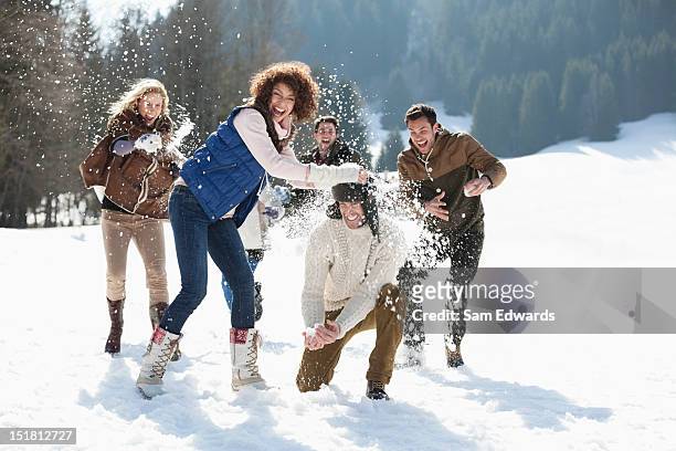 friends throwing snowballs in field - sam field stockfoto's en -beelden
