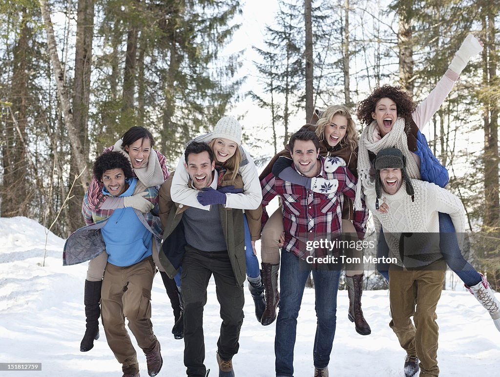 Enthusiastic couples piggybacking in snowy woods