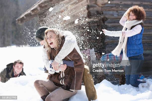 laughing friends enjoying snowball fight - snowball hit stock pictures, royalty-free photos & images