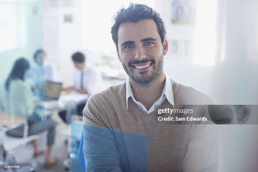 Portrait of smiling businessman in conference room with co-workers in background