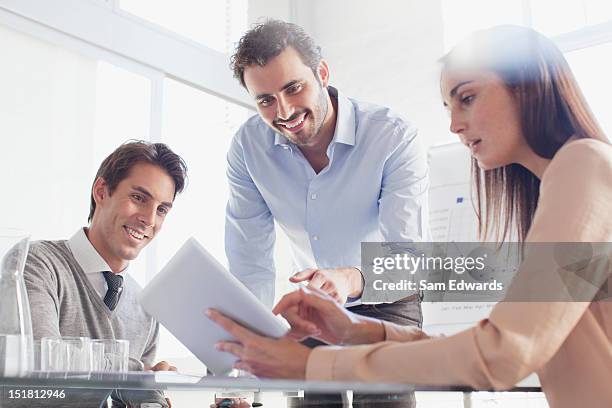 smiling business people using digital tablet in meeting - group of businesspeople standing low angle view stock pictures, royalty-free photos & images