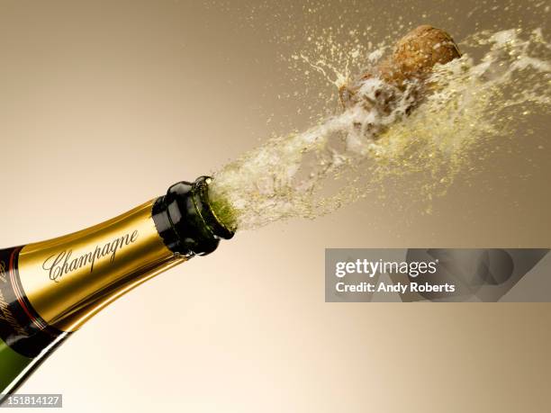 champagne and cork exploding from bottle - champagne fotografías e imágenes de stock