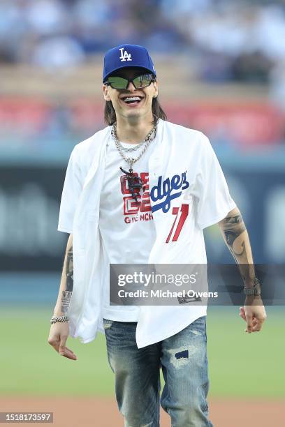 Rapper Peso Pluma reacts after throwing the ceremonial first pitch prior to a game between the Los Angeles Dodgers and the Pittsburgh Pirates at...