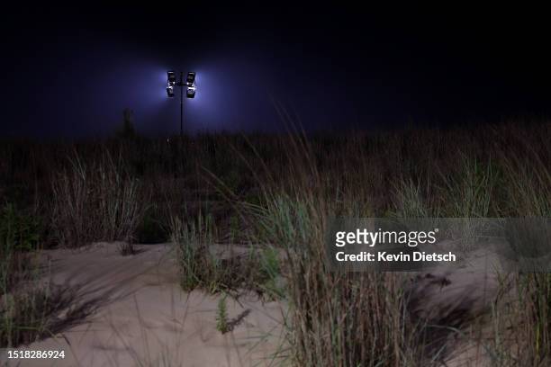 Temporary light is seen over a dune as the Army Corp of Engineers move sand as part of their beach and dune replenishment project on July 05, 2023 in...