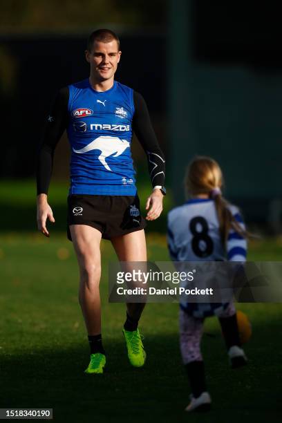 Bailey Scott of the Kangaroos kicks a football with a young fan during a North Melbourne Kangaroos AFL training session at Xavier College on July 06,...