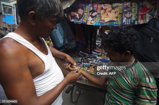 An Indian truck driver tries on a bracelet at a shop also selling adult magazines in Sanjay Gandhi Transport Nagar, a transport rest area in New...