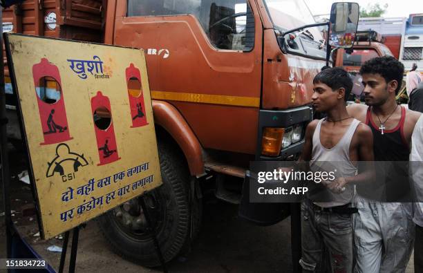 Indian truck drivers look at a board game advocating safe sex and HIV prevention, by the NGO Child Survival India, during an outreach program at...