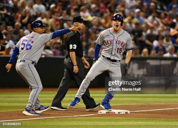 Mark Canha of the New York Mets celebrates hitting an RBI triple as third base coach Joey Cora points to second base against the Arizona Diamondbacks...