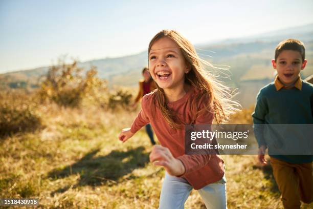 glückliche kleine kinder, die sich am herbsttag auf einer wiese amüsieren. - kinder rennen stock-fotos und bilder