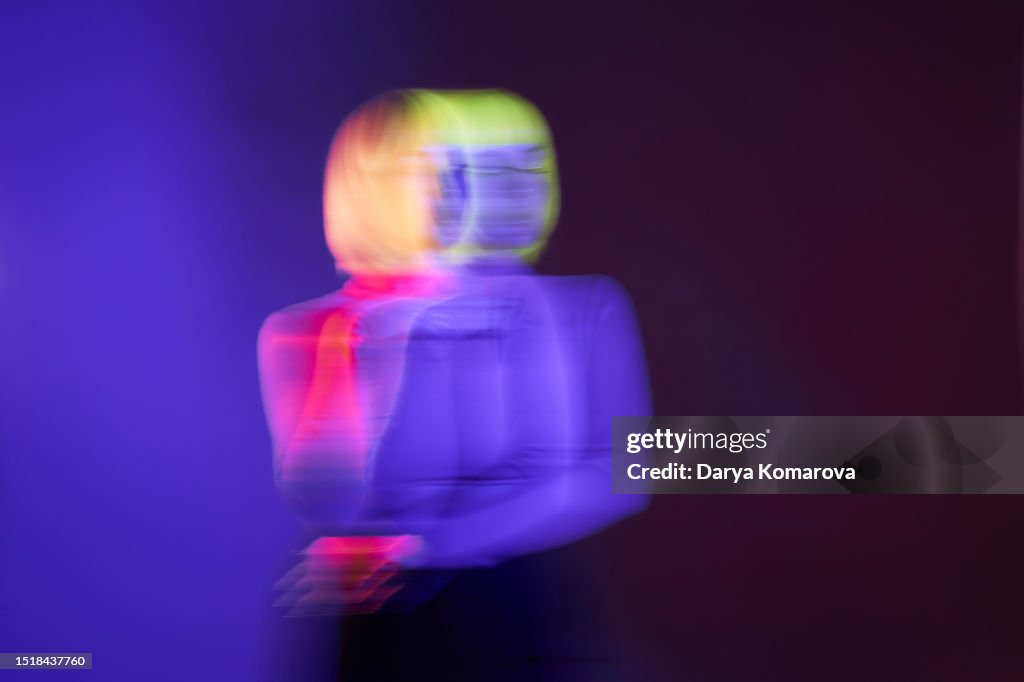Futuristic portrait on the move of young woman with yellow hair and purple face. Neon lighting and trendy colours, mock-up for your design with copy space.