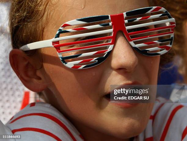 Young fan wearing a spectacle frame in the colors of the Union Jack waits in the heat for the arrival of Britain's Prince Williams and his wife...