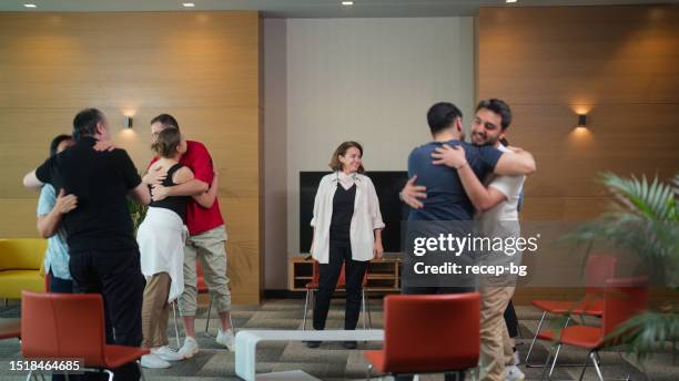 mental health professional finishing group therapy session and all participants hug each other - victim assistance stock pictures, royalty-free photos & images