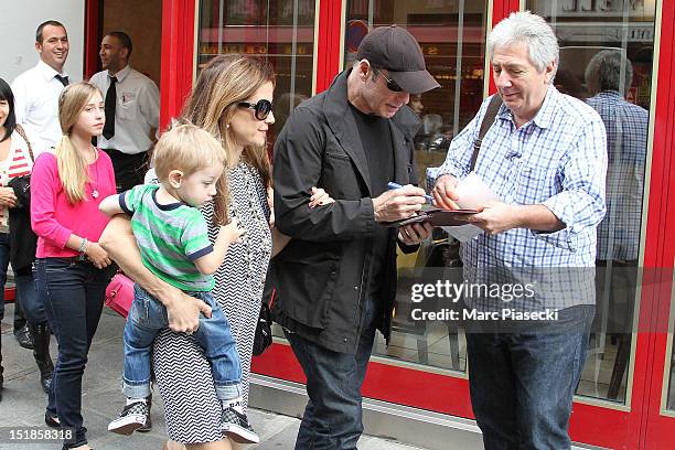 Actor John Travolta signs autographs as he and his wife Kelly Preston, their son Benjamin and their daughter Ella Bleue are seen leaving the 'Pizza...