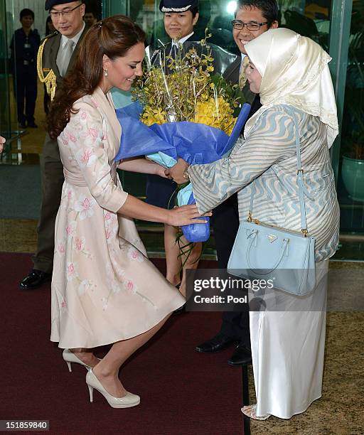 Catherine, Duchess of Cambridge is presented with a bouquet of flowers as she arrives at Singapore Changi Airport during the Diamond Jubilee tour on...