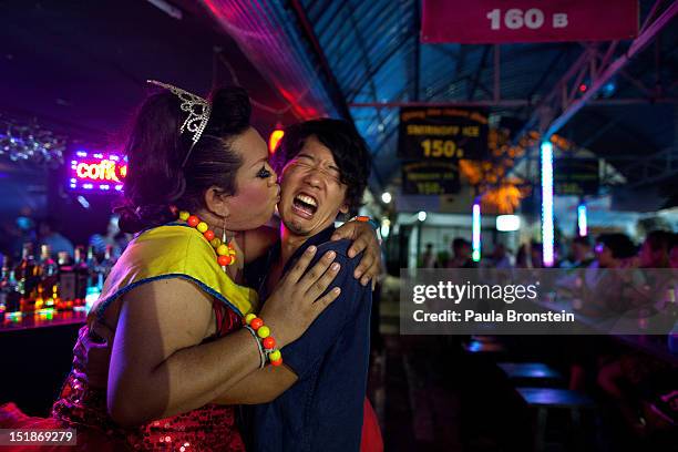 Lily throws a kiss on the cheek of a Japanese tourist as he reacts after the show at the Chiang Mai Cabaret September 9, 2012 in Chiang Mai,...