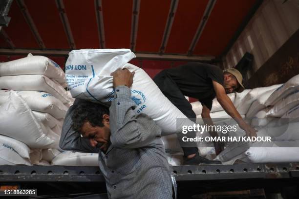 Workers unload bags of aid at a warehouse near the Syrian Bab al-Hawa border crossing with Turkey, on July 10, 2023. Negotiations continued at the...