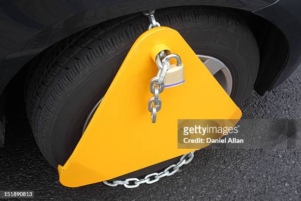 a wheel clamp padlocked on a car wheel - sabot de denver photos et images de collection