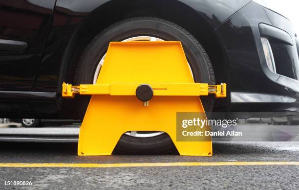 a wheel clamp attached to the wheel of a black car - tranca de roda - fotografias e filmes do acervo
