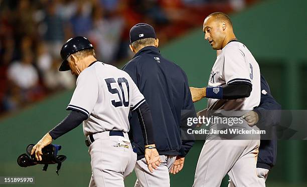 Derek Jeter of the New York Yankees walks off of the field with first base coach Mick Kelleher and manager Joe Girardi after injuring himself on a...