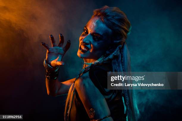 profile photo of merciless furious valkyrie woman grin teeth arm scare orange blue lights isolated on dark background - barbarian fotografías e imágenes de stock