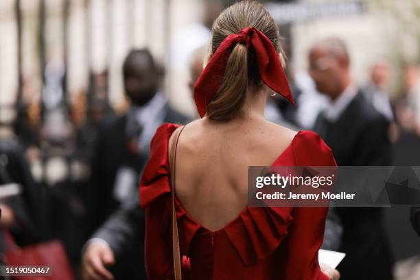 Guest seen outside Zuhair Murad show wearing red hair bow, red open back dress and Hermes Kelly bag in brown with gold hardware during the Haute...