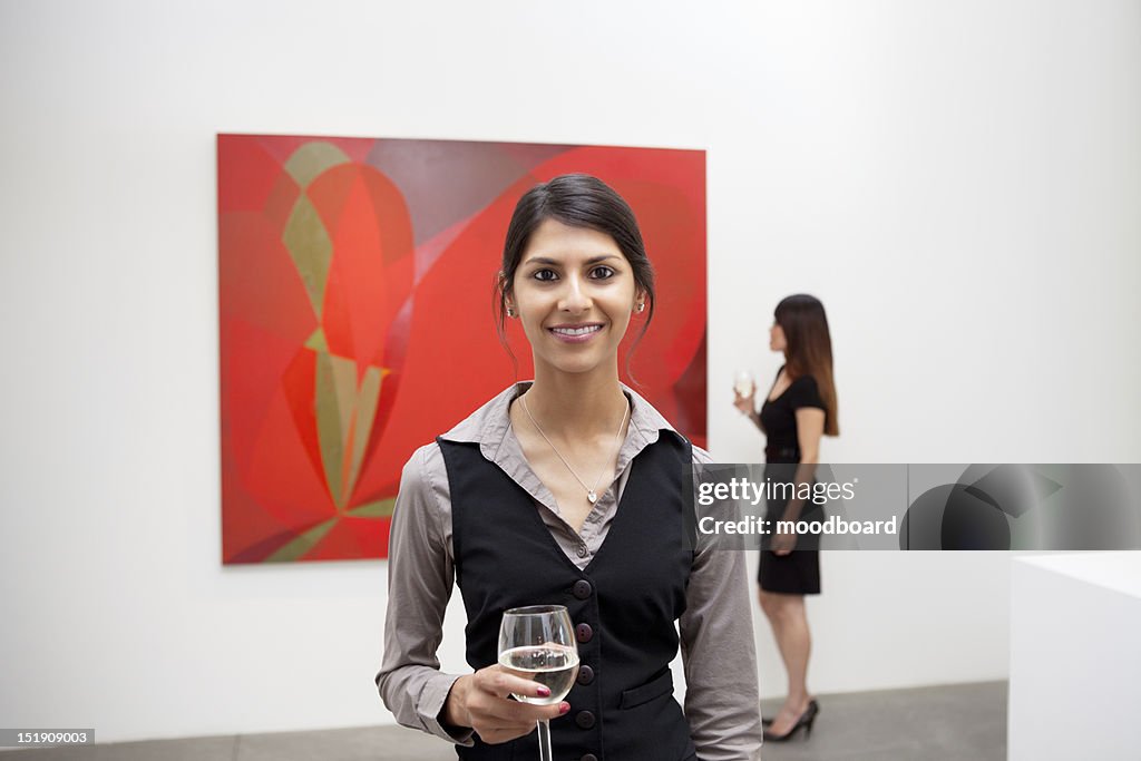 Portrait of young woman in front of painting in art gallery