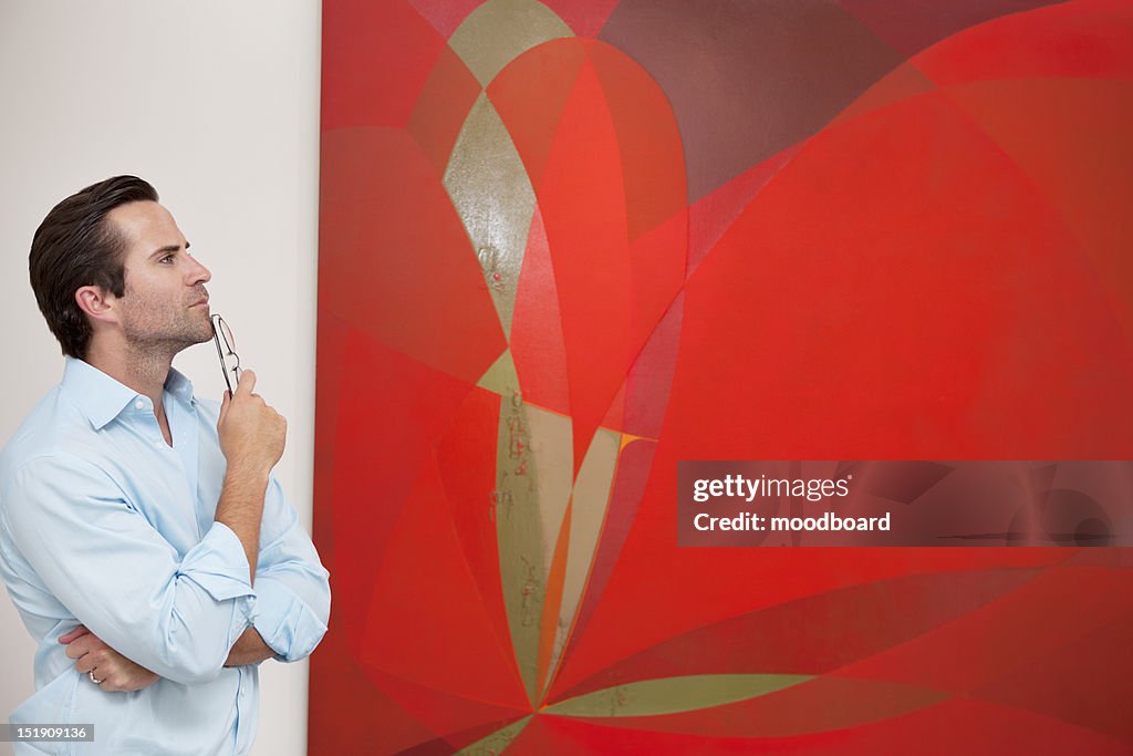 Thoughtful young man looking at painting in art gallery