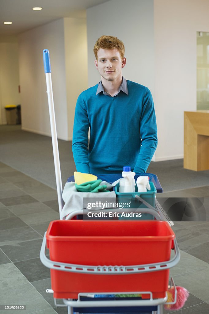 Male cleaner pushing trolley with cleaning equipment