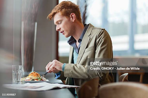 man sitting in a restaurant taking lunch - 20 24 anni foto e immagini stock