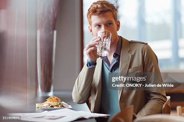 man sitting in a restaurant and drinking water - man drinking water photos et images de collection