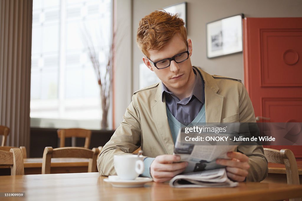 Man sitting in a restaurant and reading a newspaper