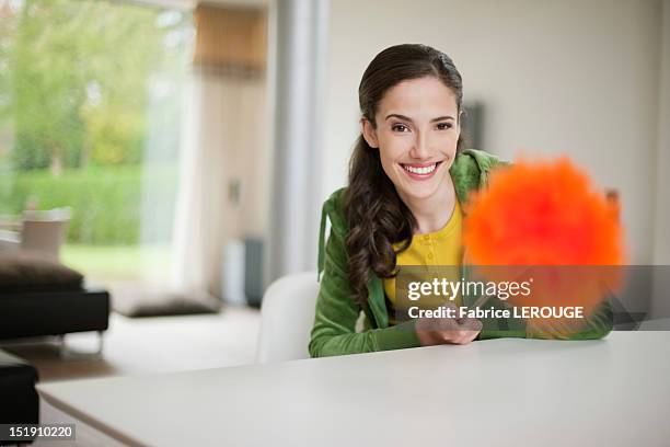 happy woman holding a feather duster - duster stock-fotos und bilder