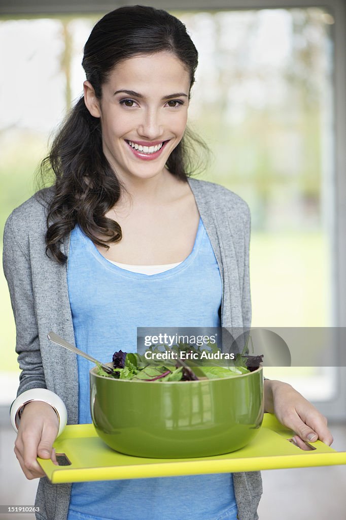 Woman carrying a bowl of salad on a tray