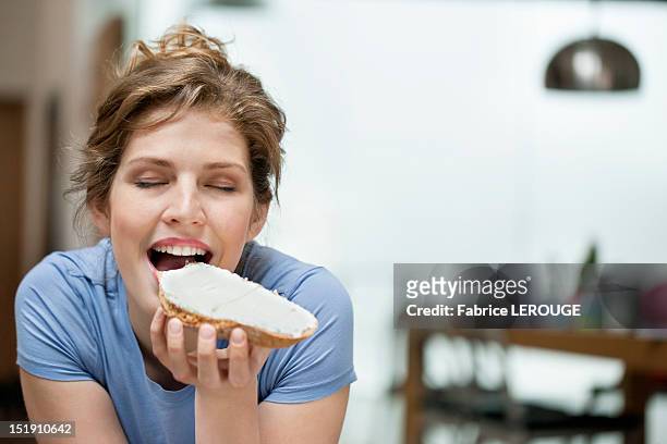 woman eating toast with cream spread on it - cheese spread ストックフォトと画像