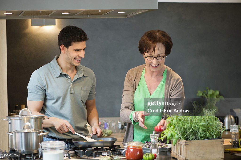 Woman assisting her son to cook food in the kitchen