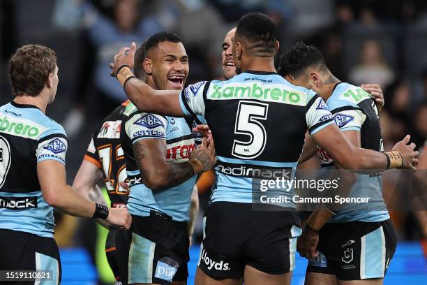 Sione Katoa of the Sharks celebrates with team mates after scoring a try during the round 19 NRL match between Wests Tigers and Cronulla Sharks at...