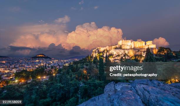 evening view over athens with the acropolis illuminated - acropolis athens stock pictures, royalty-free photos & images