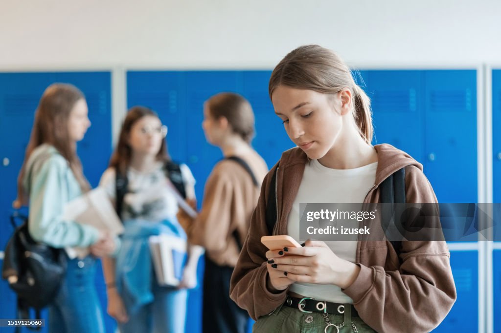 Portrait of female high school student using phone