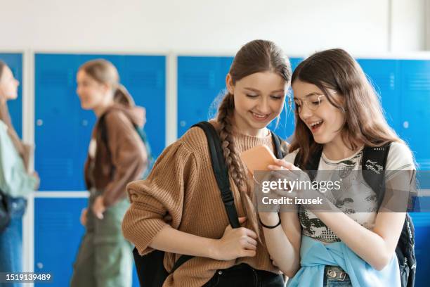 ragazze adolescenti che usano lo smartphone nel corridoio della scuola - nativo digitale foto e immagini stock