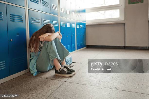 adolescente preocupada sentada en el suelo de la escuela - acoso escolar fotografías e imágenes de stock