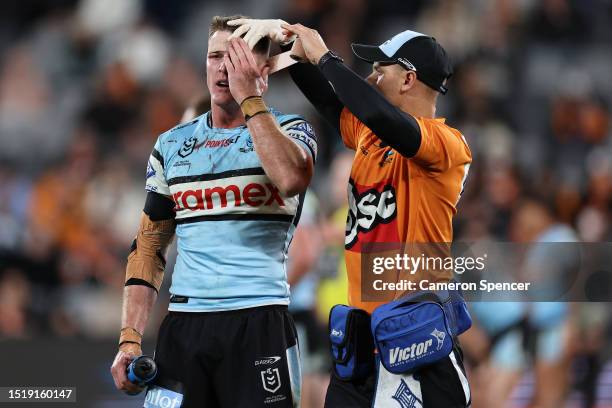 Teig Wilton of the Sharks has his head taped by a trainer after a head injury during the round 19 NRL match between Wests Tigers and Cronulla Sharks...