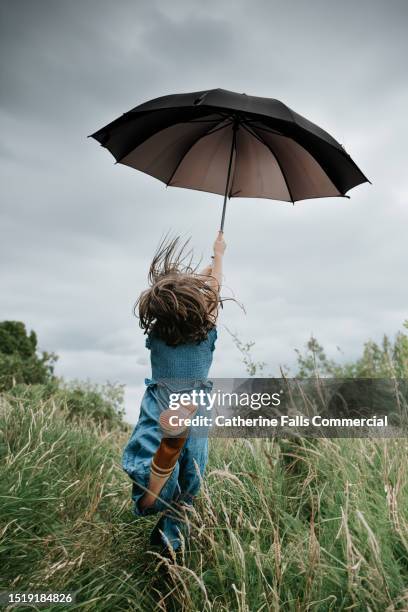 a child loses control of her umbrella on a windy day - regenschirm stock-fotos und bilder