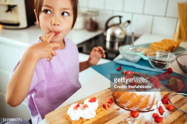 chica disfrutando de pastel en la cocina - cupcakes girls fotografías e imágenes de stock