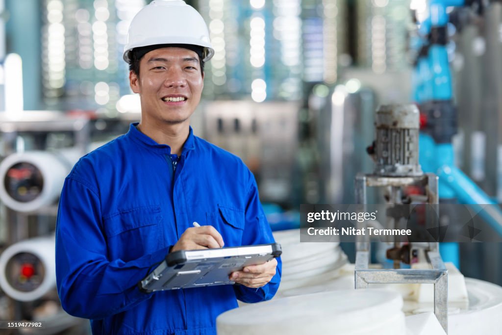 Water Pumping Station Monitoring System in the Food Processing Industry. A male Japanese service engineer in the water pumping control room to check performance and reliability of the pumping station via a tablet computer.