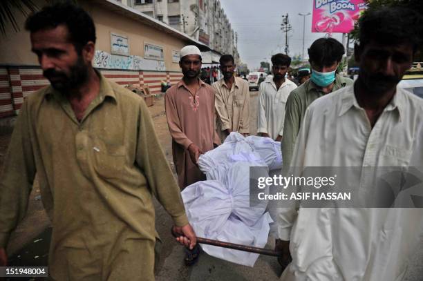 Pakistani men carry the coffin of their relative who died in a garment factory fire from the EDHI Morgue in Karachi on September 13, 2012. More than...