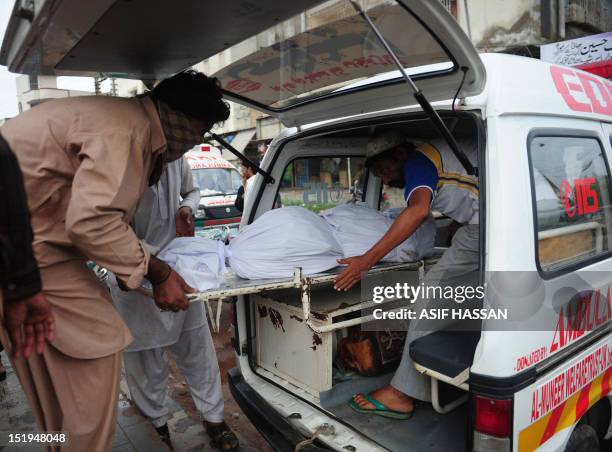 Pakistani men move the body of their relative who died in a garment factory fire into an ambulance from the EDHI Morgue in Karachi on September 13,...