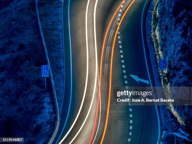 high angle view of high angle view of light trails on a curving road at night. - road light trail stock pictures, royalty-free photos & images